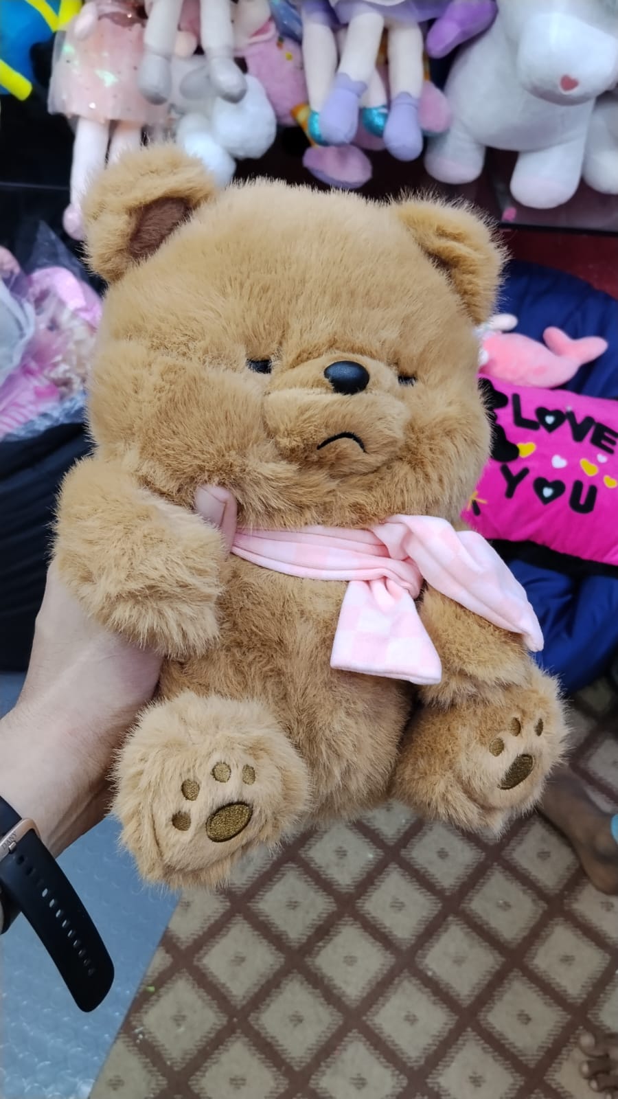 Fluffy brown teddy bear held in hand for size reference